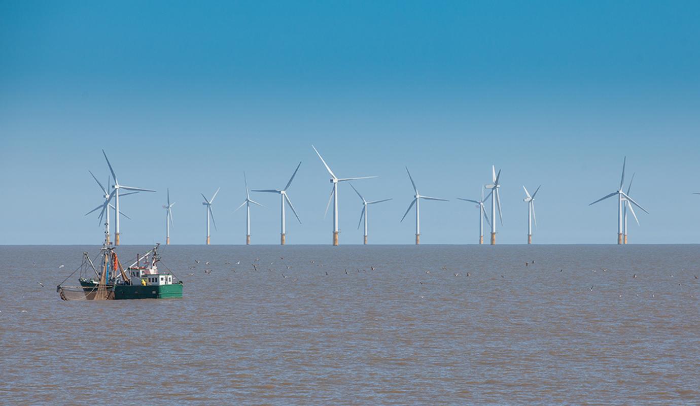 Windmolens op zee met vissersboot.